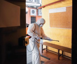 Coronavirus Pandemic. A disinfector in a protective suit and mask sprays disinfectants in house or office. Protection against COVID-19 disease. Prevention of spreding pneumonia virus with surfaces.