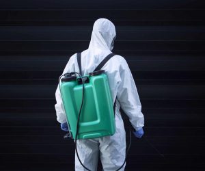 Man in white protective suit with reservoir for spraying and disinfection.
